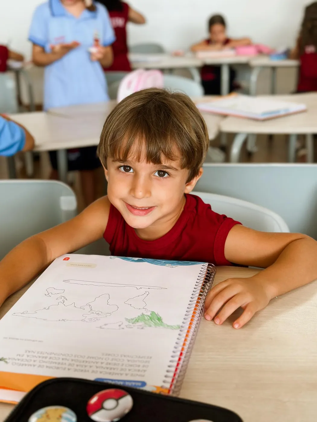 Aluno sorrindo com o caderno aberto em sala de aula