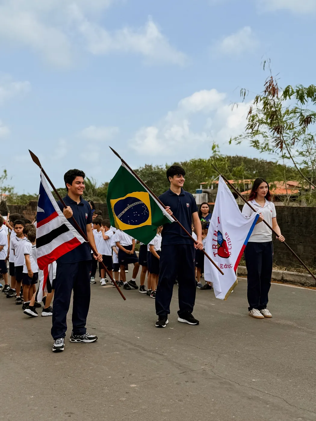 Alunos carregando as bandeiras do Maranhão, do Brasil e da escola em desfile cívico