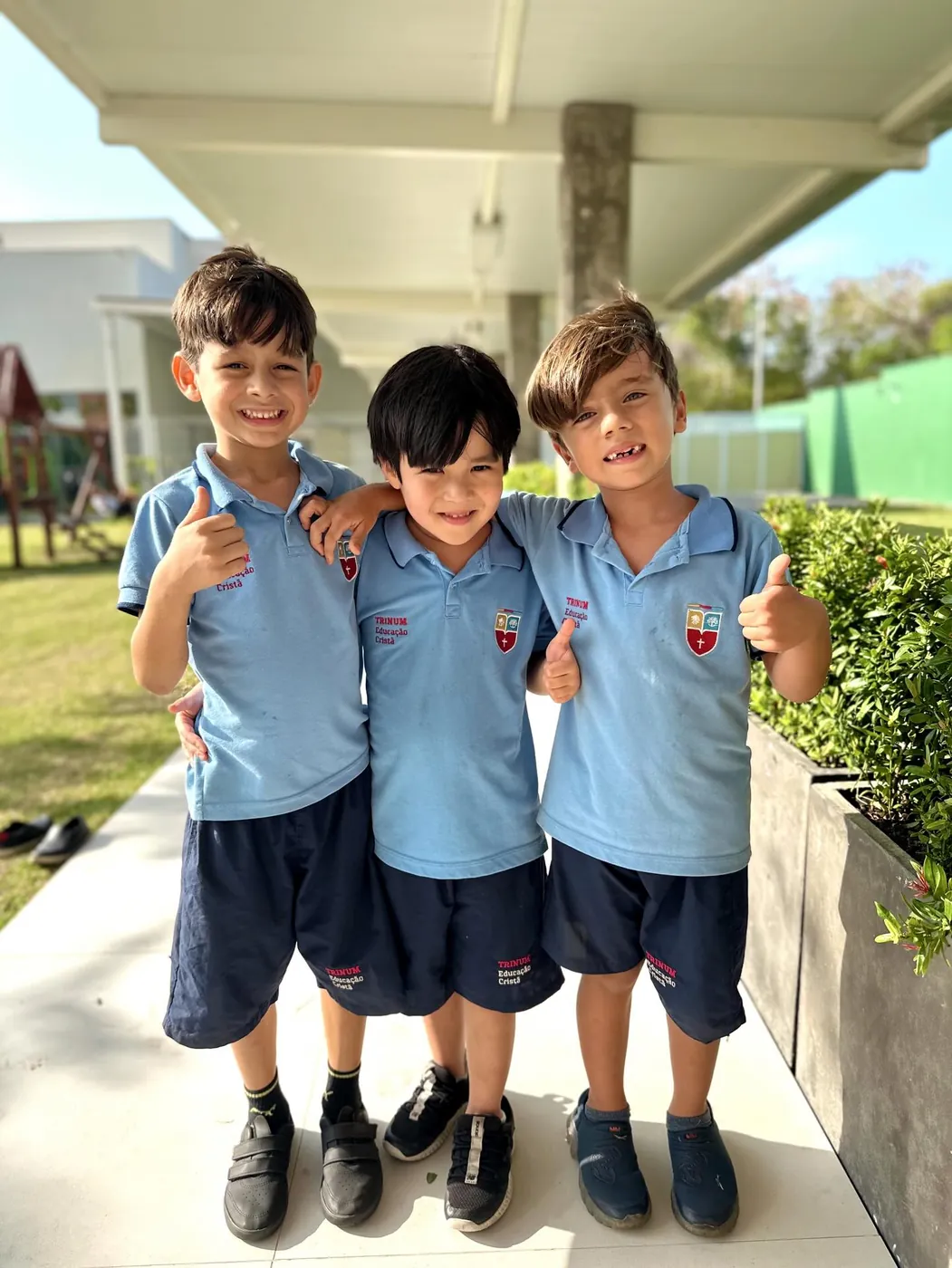 Três alunos sorrindo e fazendo sinal de positivo